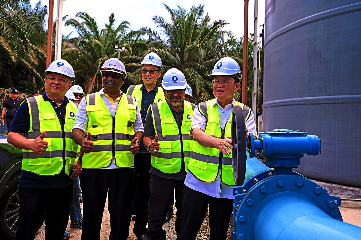 Chow turning a valve during a site visit to the Sungai Kerian compact water treatment plant. With him are Rashidi (at his right) and Pathmanathan (second from left).