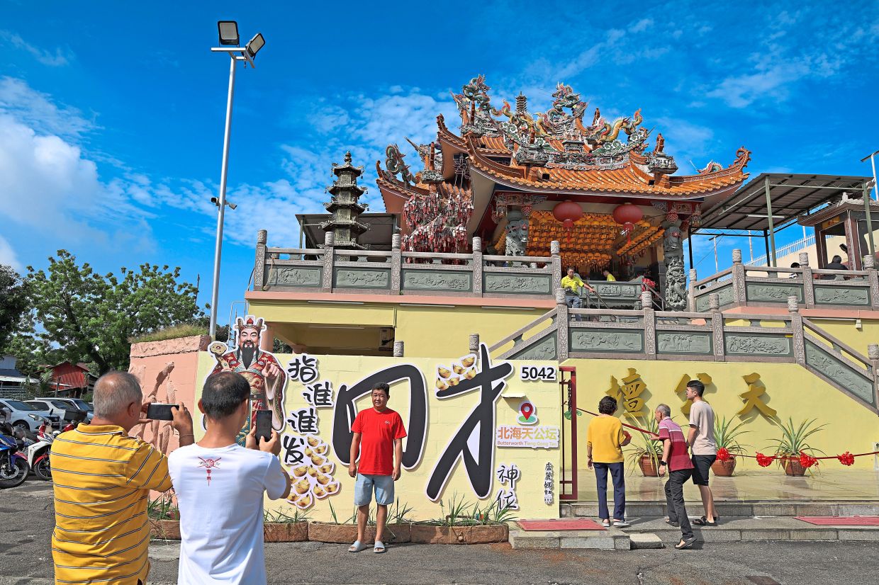 Visitors taking photos at the God of Wealth Prosperity Wall.