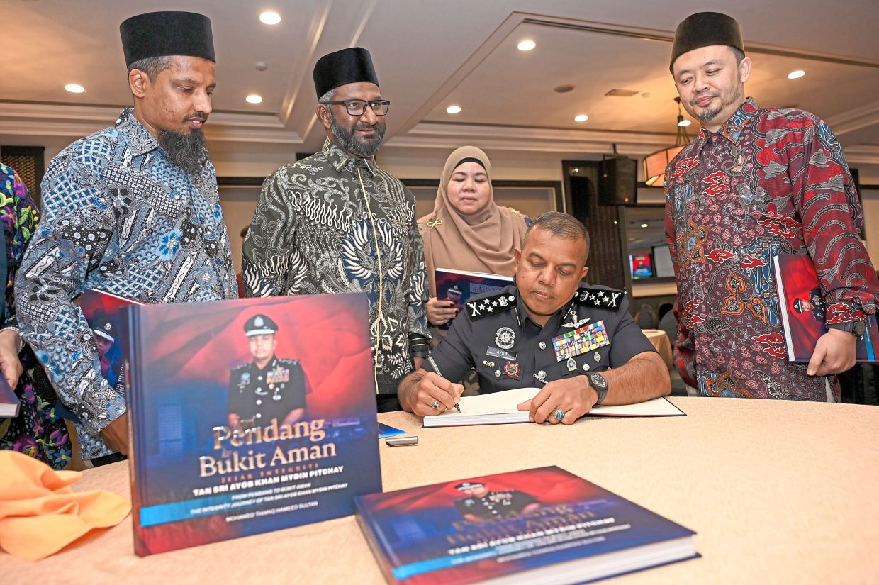 Next chapter: Ayob Khan (second right) signing a book after the launch of his autobiography in Kuala Lumpur. — IZZRAFIQ ALIAS/The Star