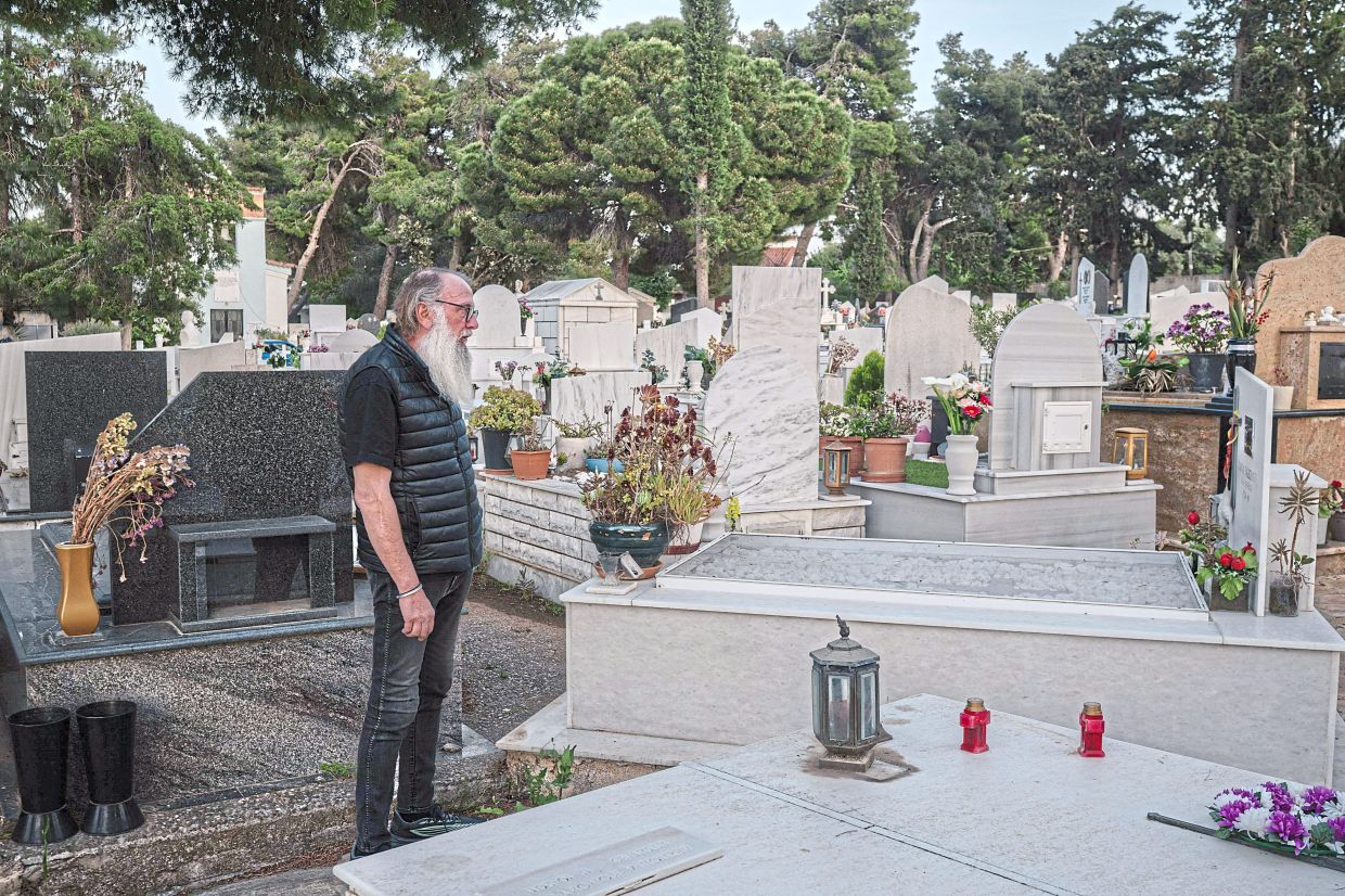 Kairis, a survivor who lost his wife, Gazeridou, in the 2018 wildfire, visiting her grave in Nea Makri, on the outskirts of Athens; (inset) a portrait of Gazeridou. — AFP