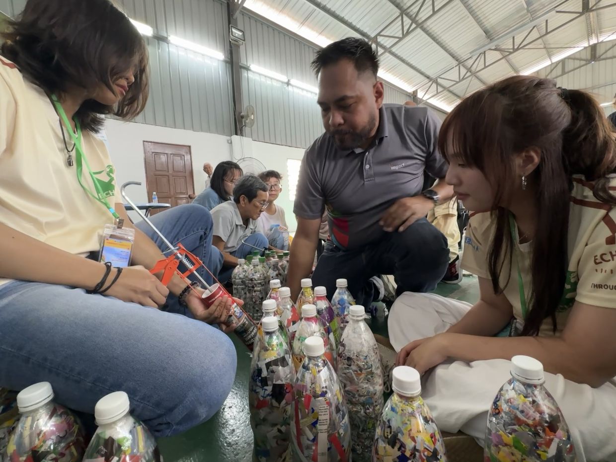 Mohd Faisal teaching student volunteers Dhiya Camalia Mahyuddin (left) and Renee Tay (right) how to ecobricks. Photo: Filepic