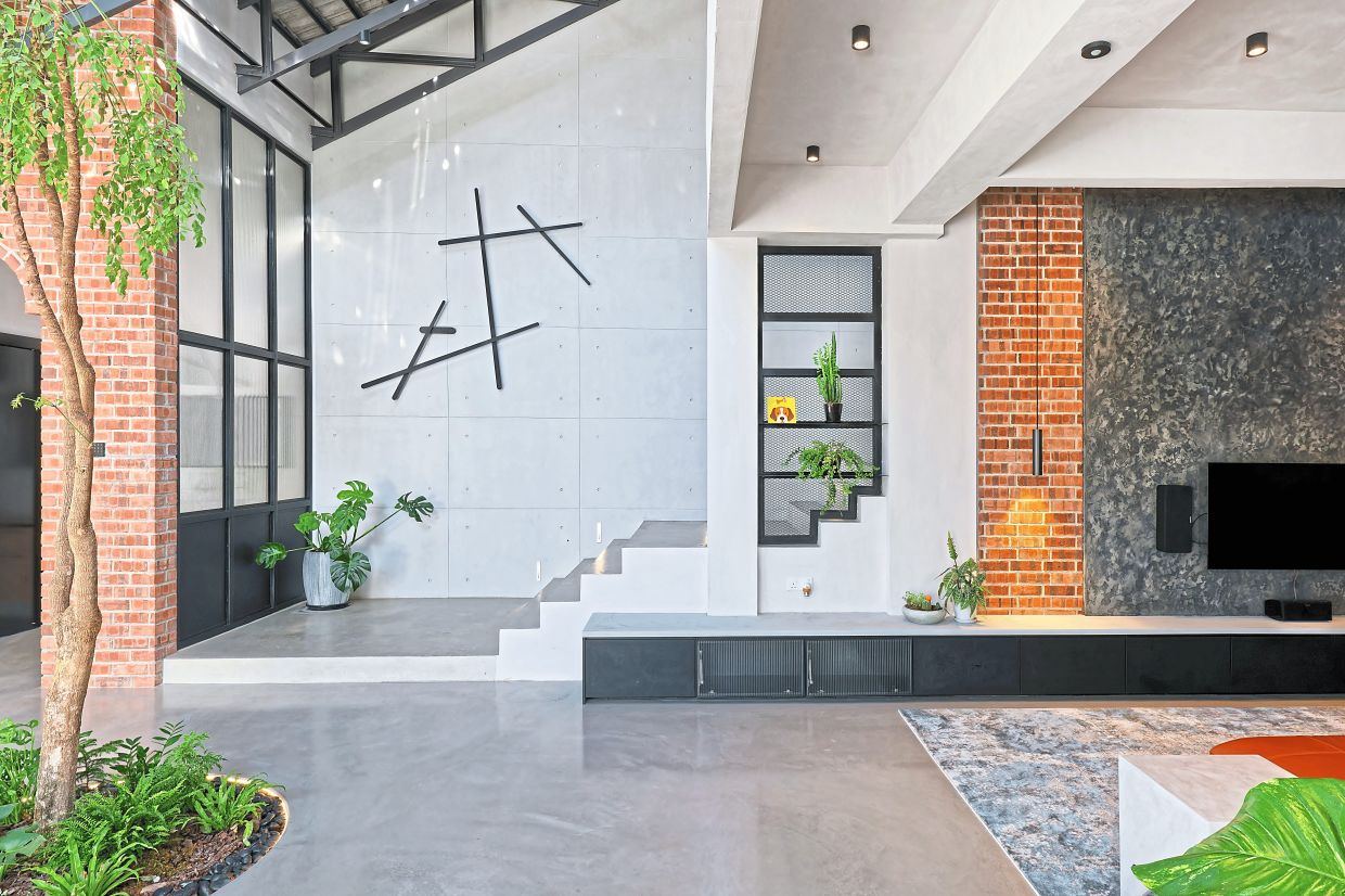 The living room with a view of the staircase and tree growing from the ground inside the house.
