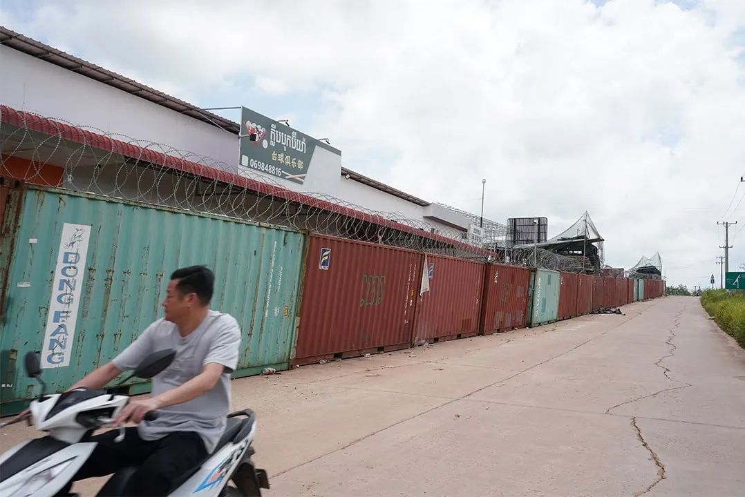 A man drives a scooter past a Thai shipping container barricade on a road in Cambodian territory at the Thmor Da area, in Pursat province. - Photo: The Phnom Penh Post/ANN