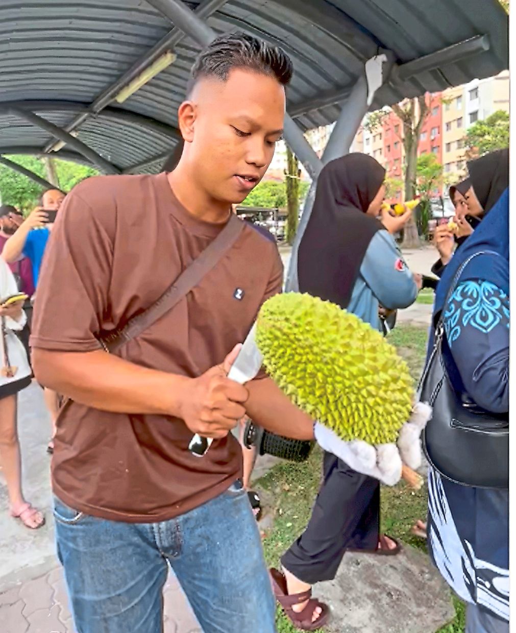 Noraliff (above) giving free durian samples to the people queuing to buy the fruit at his stall. He and his wife also gave away packets of Ikan Patin Masak Tempoyak (below) which they cooked with the excess fruits.
