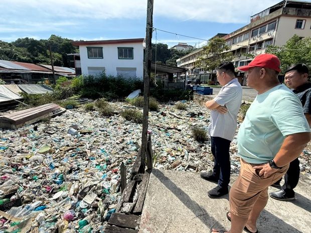 Yap Hsiu Min (left) and JKKK members surveying the rubbish-choked shoreline at Kampung Pukat.