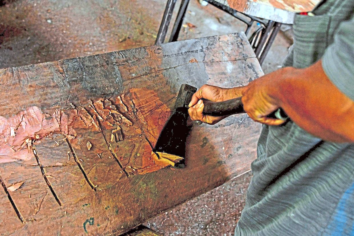 Tan hollowing out a log with an axe as part of the meticulous process of handcrafting coffins, which he says represents heritage, cultural identity and respect for the deceased.