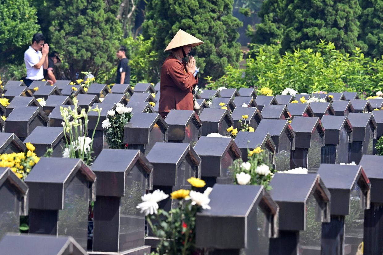A woman prays at the Ngoc Hoi Martyrs Cemetery in Hanoi on Monday, July 27, 2026, on Vietnam's War Invalids and Martyrs' Day. - Photo by Nhac NGUYEN / AFP
