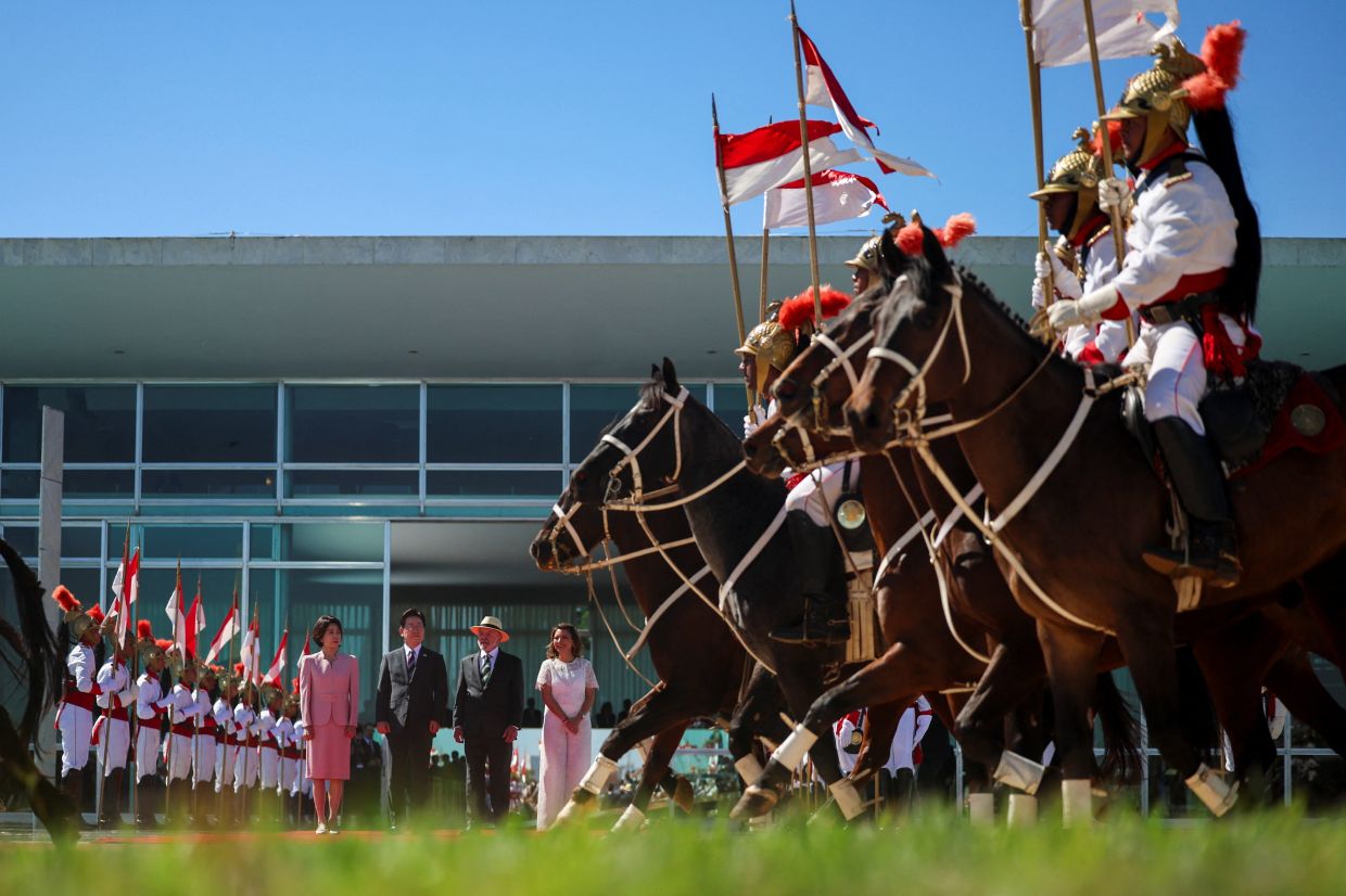 South Korean President Lee Jae Myung, flanked by his wife Kim Hea Kyung observes a presentation of troops as he is being welcomed by Brazilian President Luiz Inacio Lula da Silva and his wife Rosangela da Silva, at the Alvorada Palace in Brasilia, Brazil, on Monday, July 27, 2026. -- REUTERS/Adriano Machado