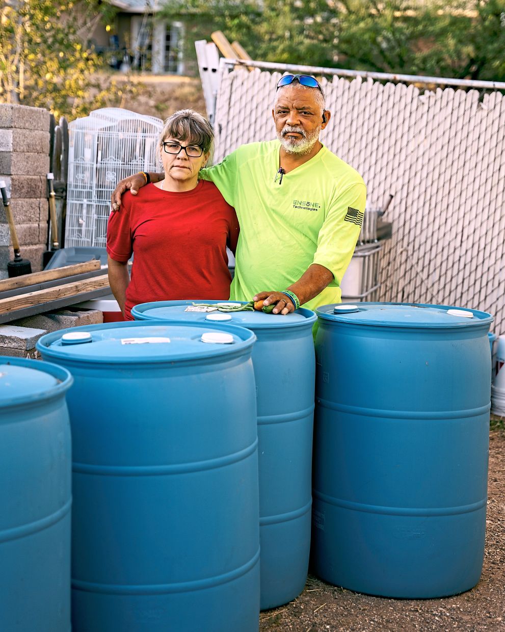 Daniel and Jenna Sostre with the barrels that they use to store water at their home in Kearny, Arizona. — Will Warasila/The New York Times