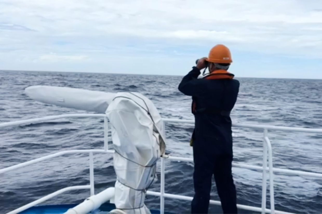 In this photo taken from video provided by the Philippine Coast Guard, a member of the Philippine Coast Guard (PCG) on board the BRP Malapascua (MRRV-4403) continues its search and rescue operations in the vicinity waters off a Chinese-occupied shoal in the South China Sea, Tuesday, July 28, 2026, following the reported sinking of Vietnamese cargo vessel Khoi Nguyen 18. -- Philippine Coast Guard via AP