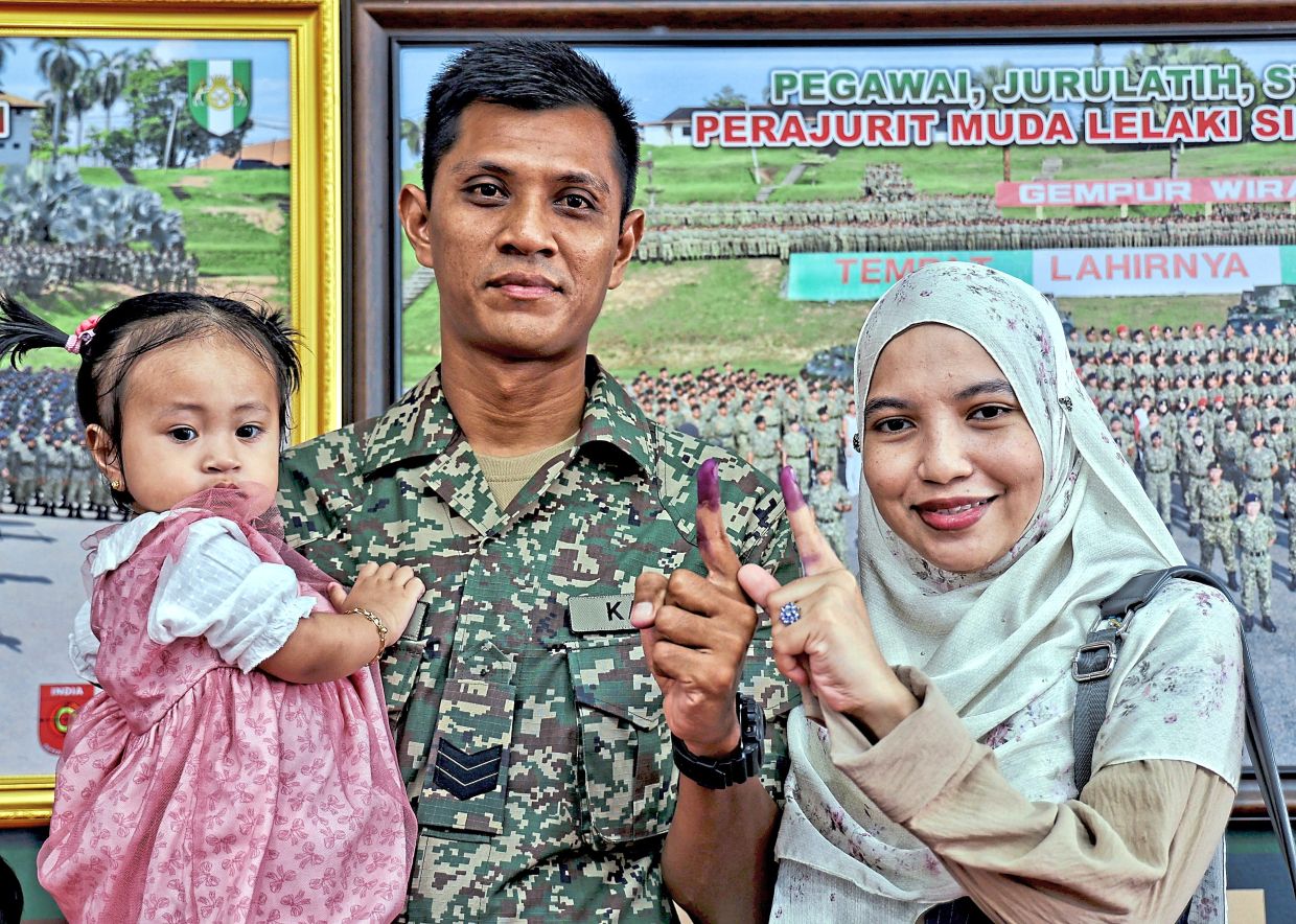 Sarjan Muhamad Amirul Ariff and his wife Hamiza Mohd Salleh show their fingers dipped in blue ink after voting at the Army Basic Training Centre in Port Dickson.