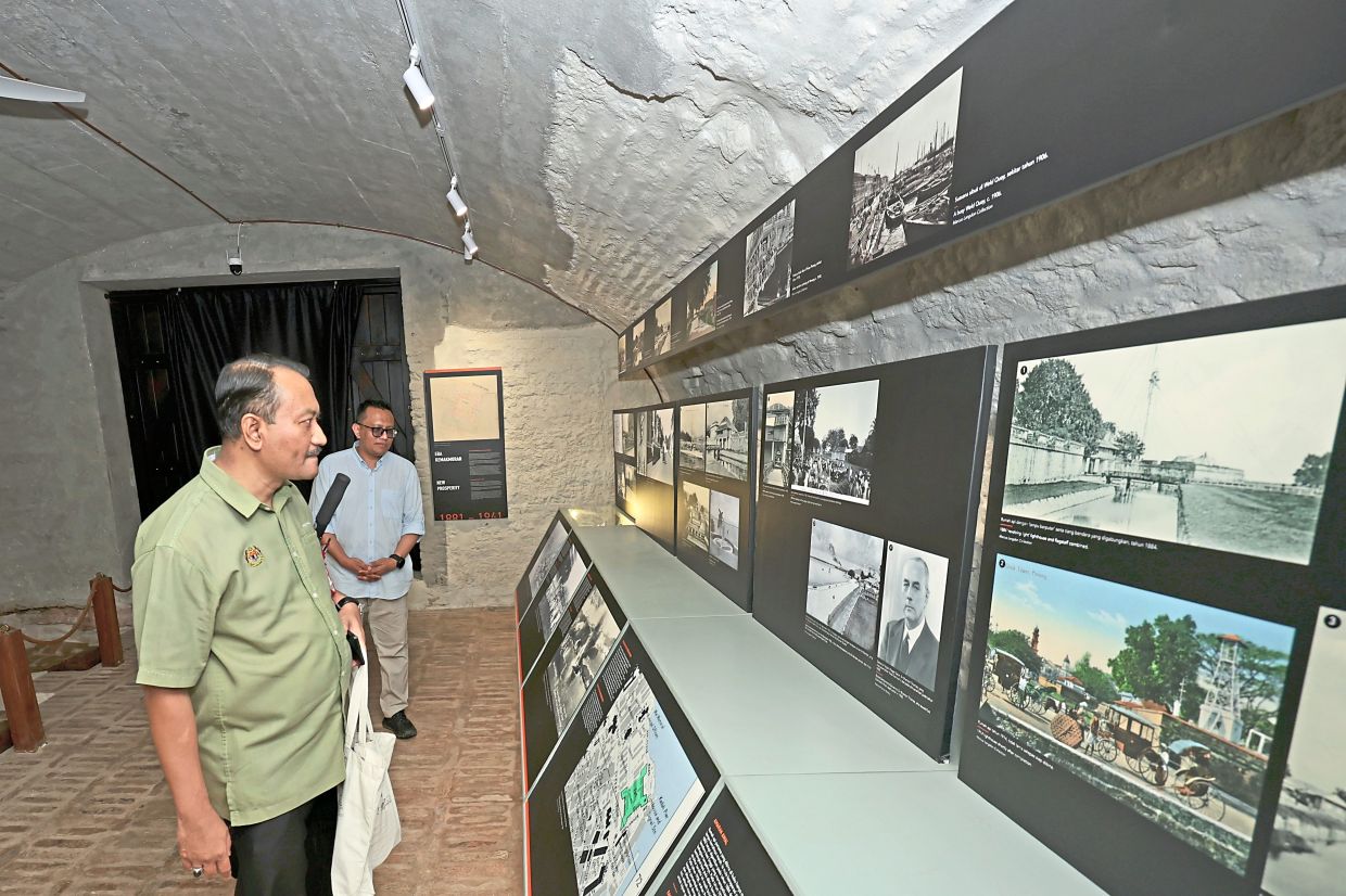 Visitors checking out the historical photograph exhibition and (below) watching a historical documentary projected onto the wall of a restored vaulted brick room at Fort Cornwallis.