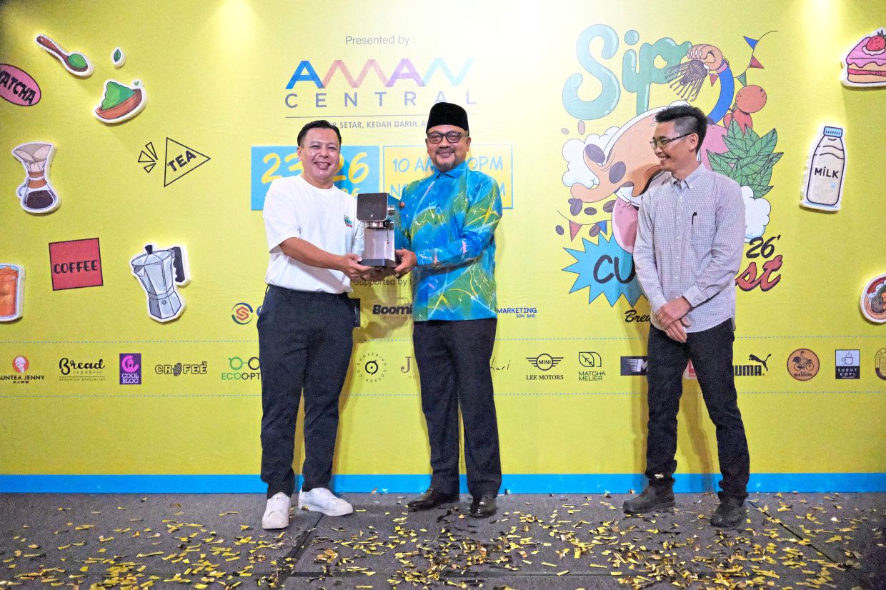 Chin (left) presenting a coffee-maker to Abdul Gafar. Looking on is Aman Central senior manager, operations, Gan Poh Hin.