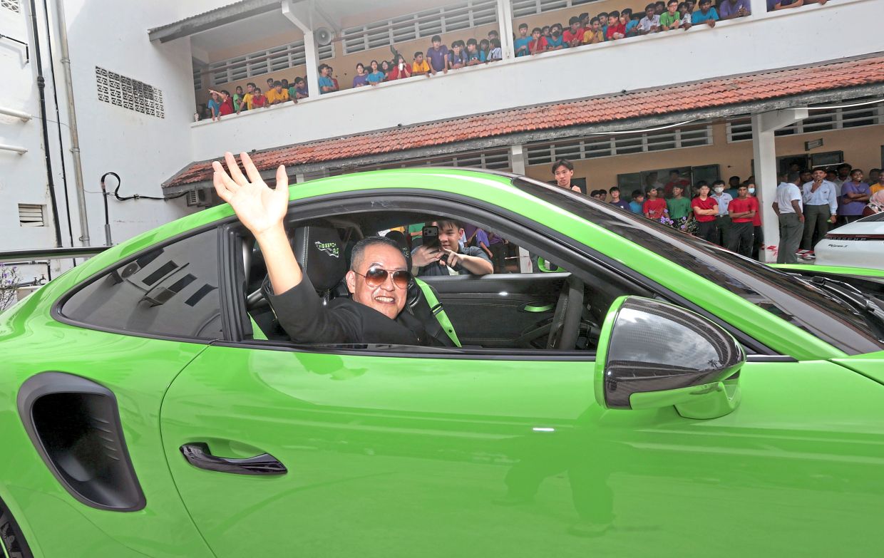 Koay waving from a Porsche 911 GT3 RS as he leaves St Xavier’s Institution after receiving a memorable farewell from hundreds of students and staff.