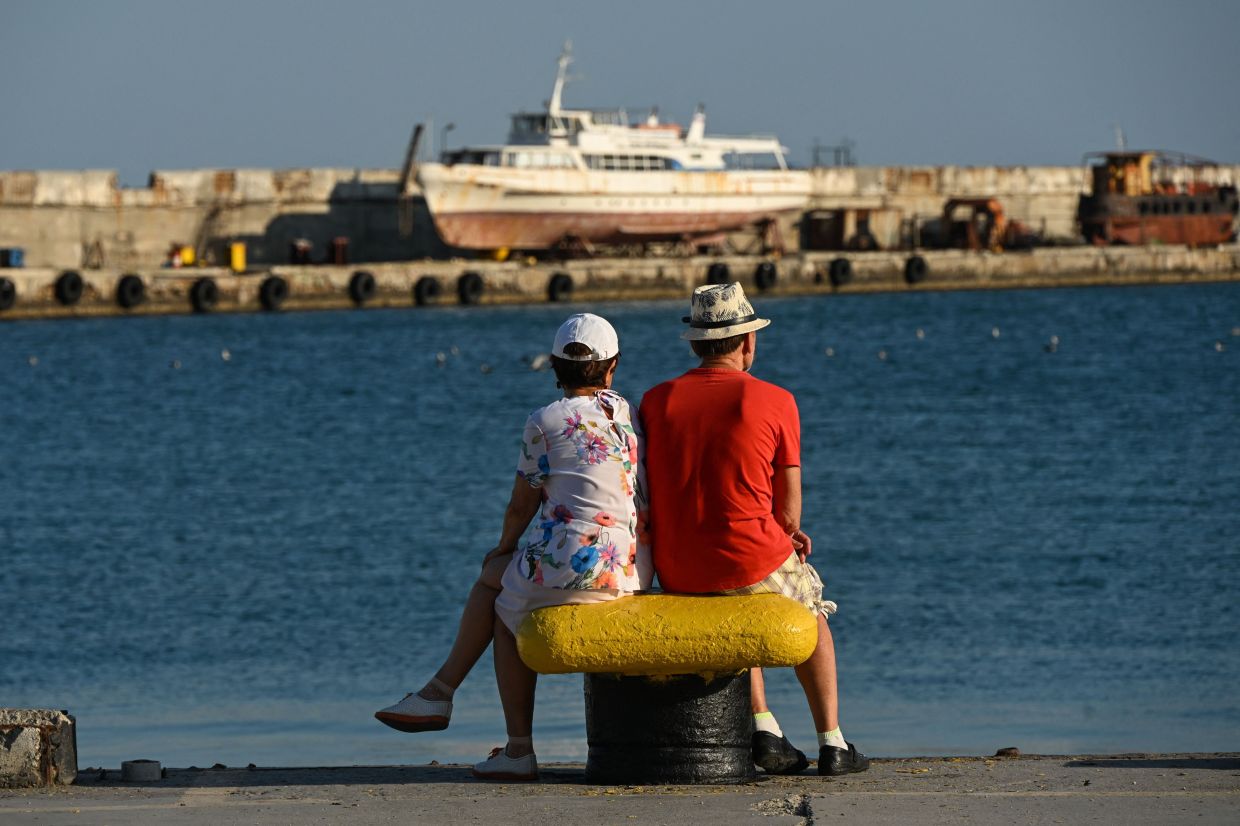 People sitting on an embankment in Yalta on the Crimean Peninsula. — AFP