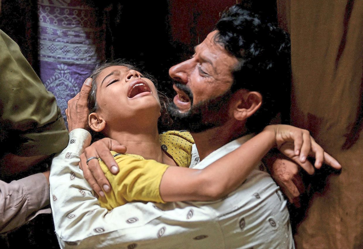 Unbearable loss: A father and daughter mourning the loss of family members who were killed when the roof of their home collapsed in Lahore, as ambulances transport the victims to the hospital. (below)— Reuters/AP