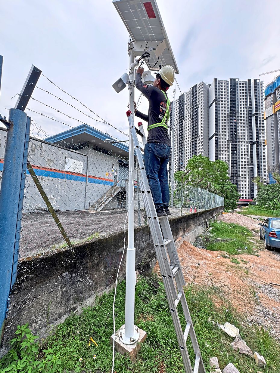 A contractor setting up a CCTV at the entrance of Jalan Bandar Kinrara 1/8 to catch those dumping waste illegally. 