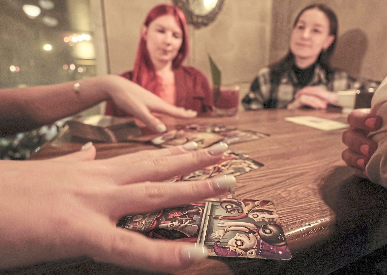 A fortune teller lays out Tarot cards on a table in the voodoo-themed bar Marie Laveau in Moscow. — Reuters
