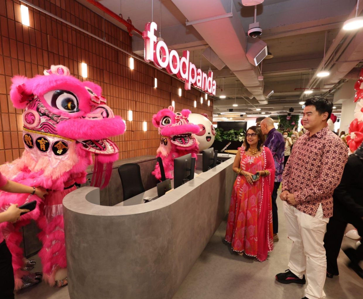 Delivery Hero MYSSC people director Deena Marie Ferns (left) and Soh (right) watching the lion dancers make their way around the office during the MYSSC opening ceremony.
