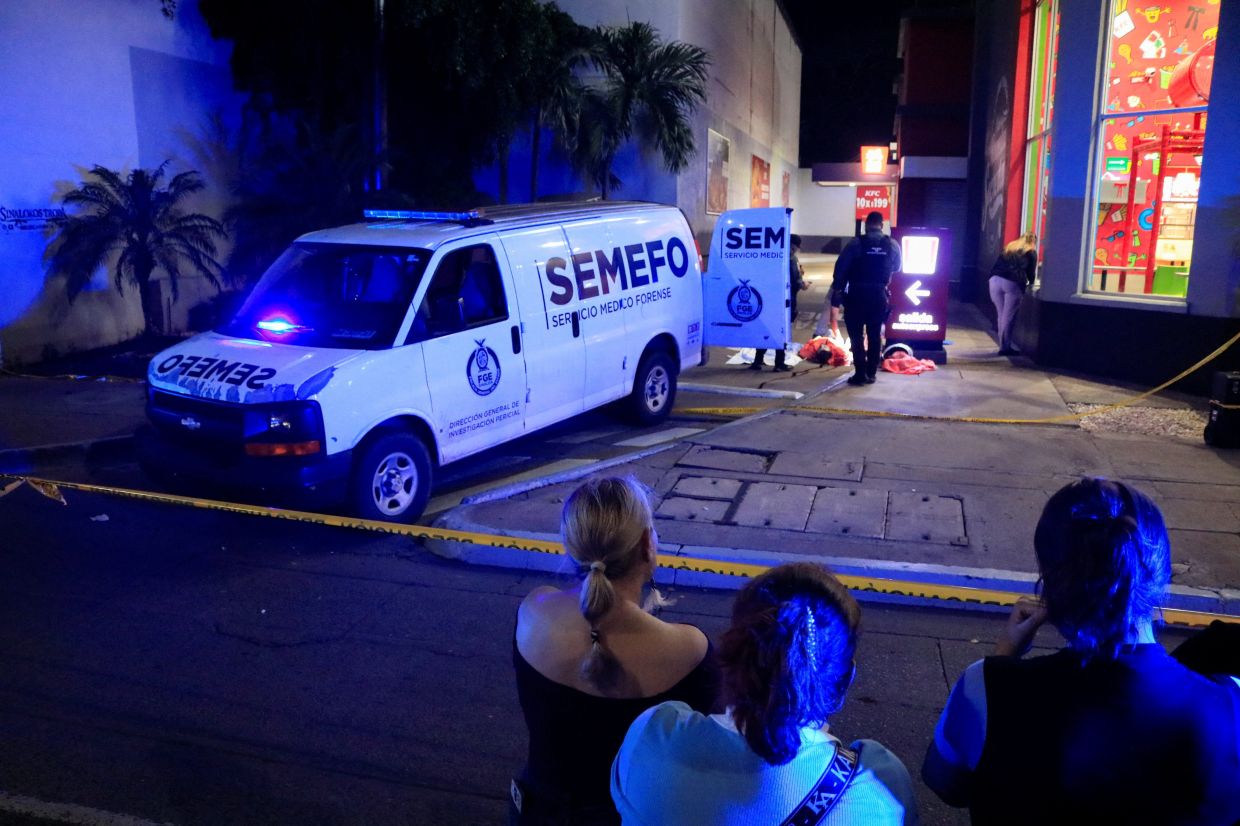 Onlookers stand behind a police cordon as forensic technicians and police officers work at the crime scene where Mexican social media influencer Cesar Gastelum was shot and killed. Photo: Reuters