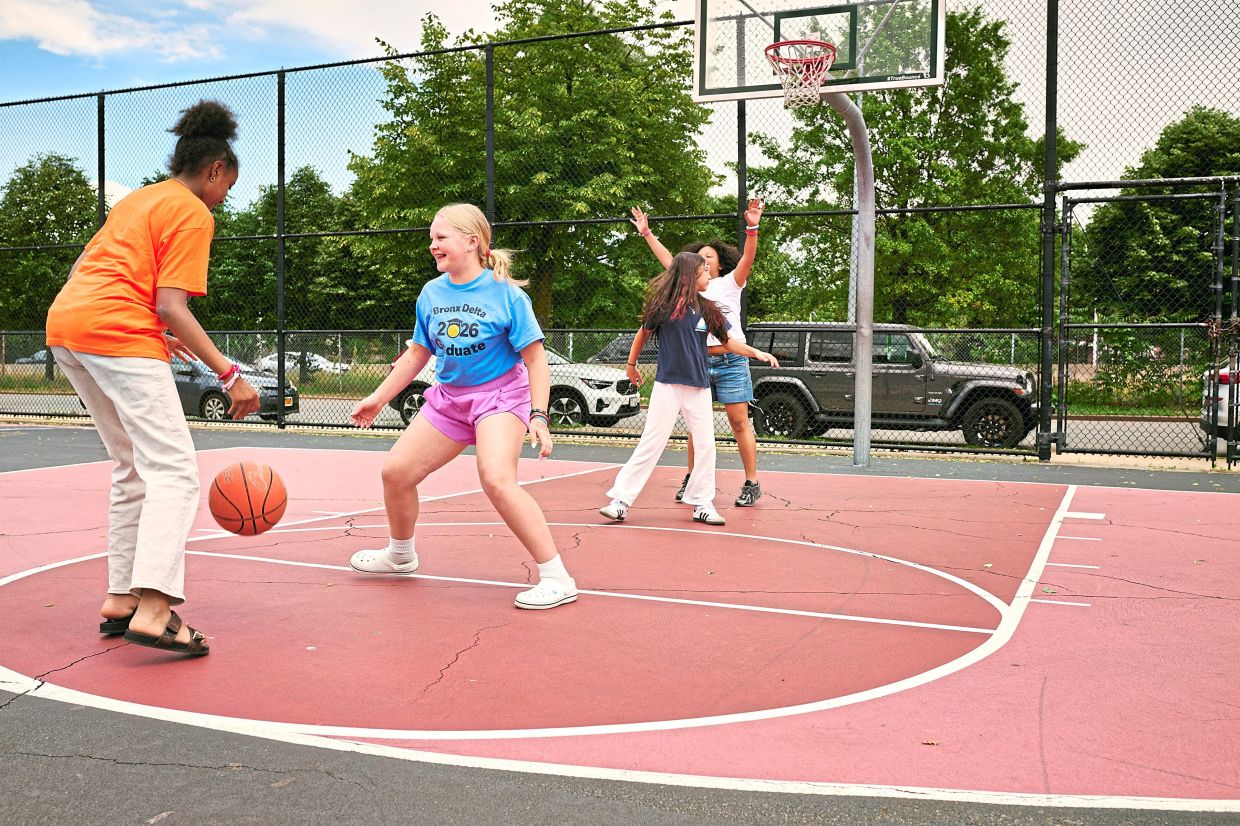 Children at the shared playground at Bronx Delta School, where one half-court was painted pink while the other three half-courts and the full court were painted blue.