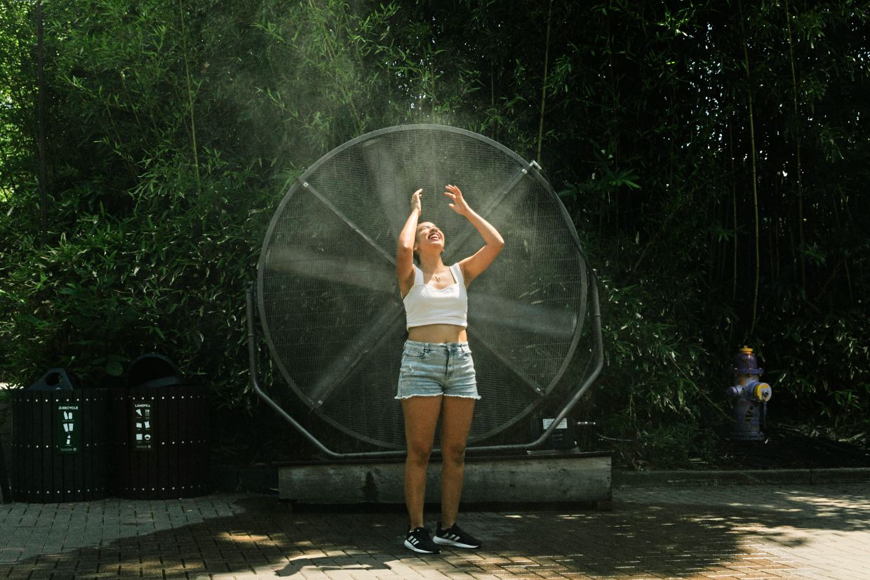 A visitor cools off in front of a fan with a mister.