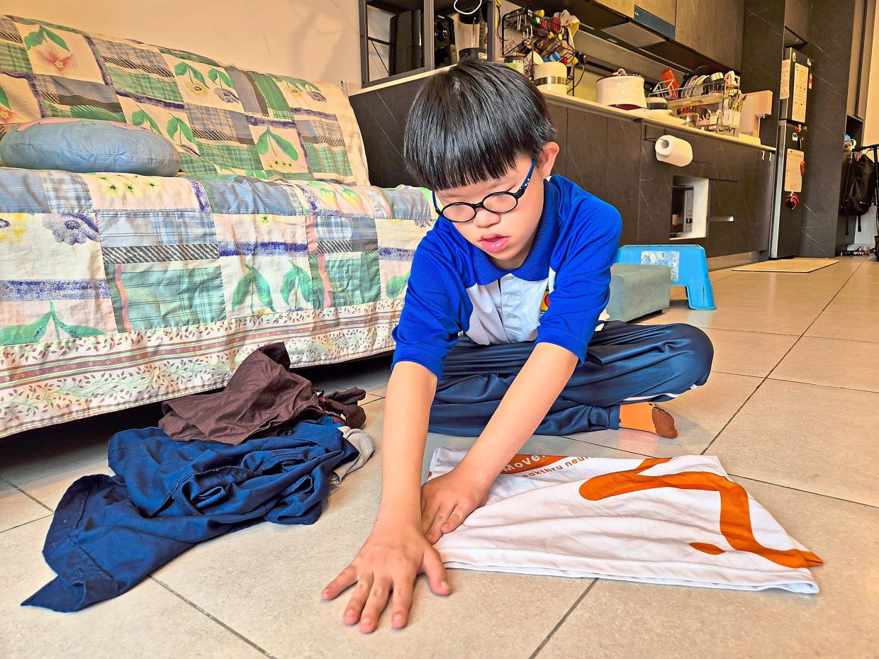 Hau Tze learns practical skills such as folding clothes so he can be more independent. Photo: The Star/Sheela Chandran