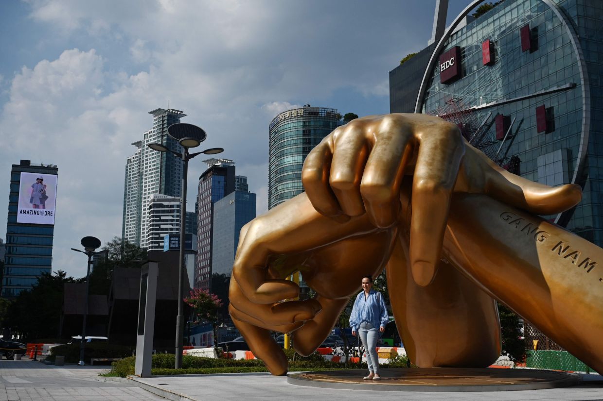 A woman poses for photos at the Gangnam Style sculpture by South Korean artist Hwang Man-seok, in the style of the horse-riding dance move from the music video of the K-pop song Gangnam Style by South Korean singer Psy, at the COEX Mall in Seoul on Friday, August 7, 2026. -- Photo by GREG BAKER / AFP