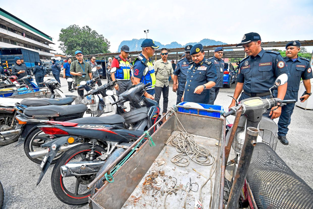 Selangor JPJ director Datuk Ahmad Kamarunzaman Mehat (third right) looking at seized vehicles after ‘Ops Pemandu Warga Asing’ in Selayang. — Filepic
