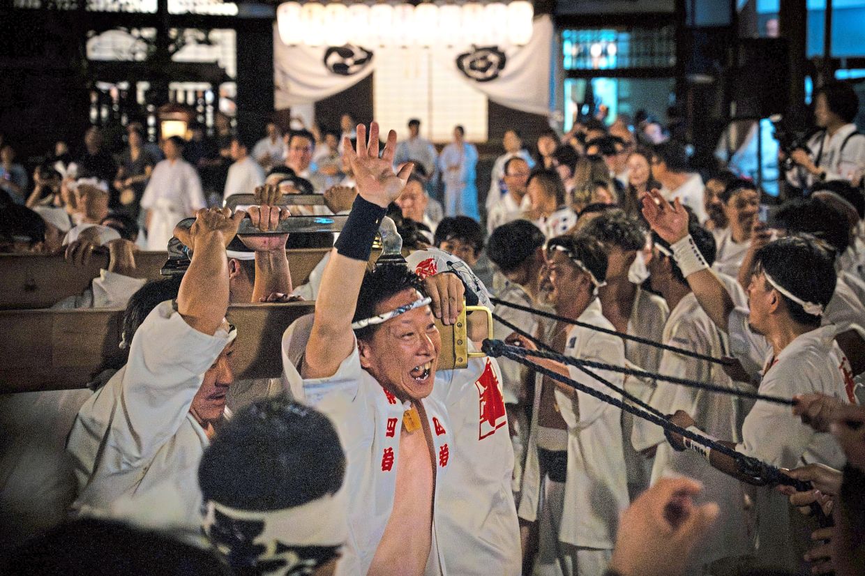 Festive cheer: Festival participants carrying Yasaka Shrine’s Eastern Mikoshi back into the shrine’s main hall. — AP