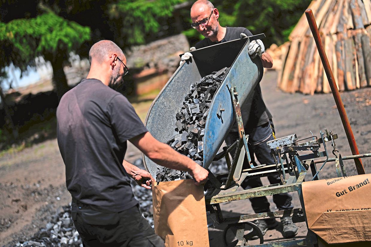 Feldmer (right) and Sascha put charcoal into paper bags after weighing it.