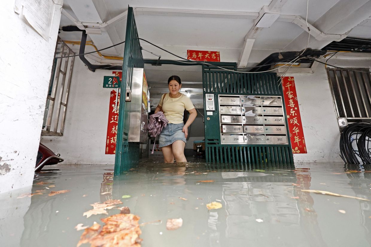 A resident wades through floodwaters at a residential compound following heavy rainfall as Typhoon Dolphin approaches, in Shanghai, China, Aug 9, 2026. - Photo: Reuters