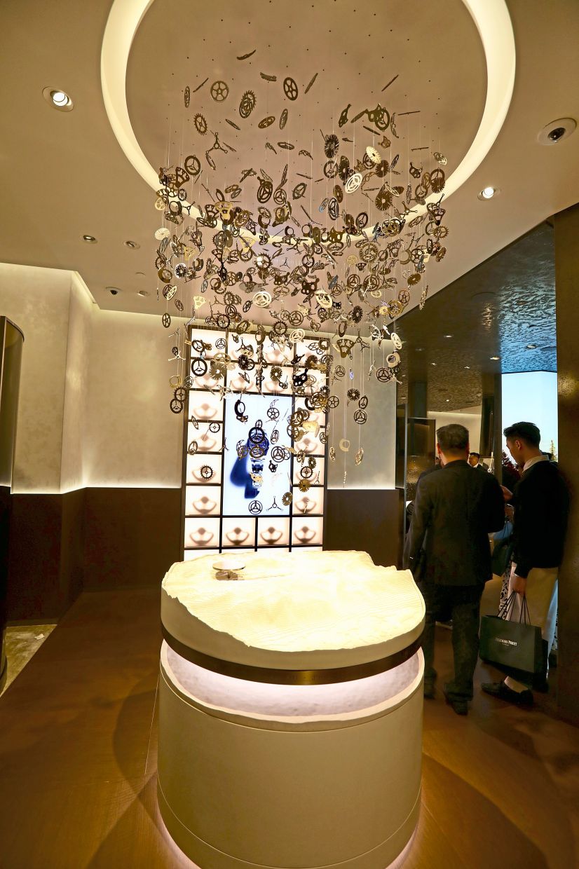 A horological sculpture composed of hundreds of enlarged watch components hang from the ceiling.