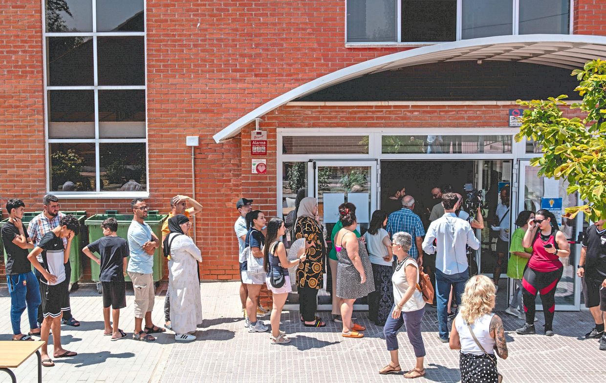 People queue for meals at the La Chopera sports hall in Madrid,a temporary accommodation for people fleeing wildfires, on July 26. — Joseph Fox/The New York Times