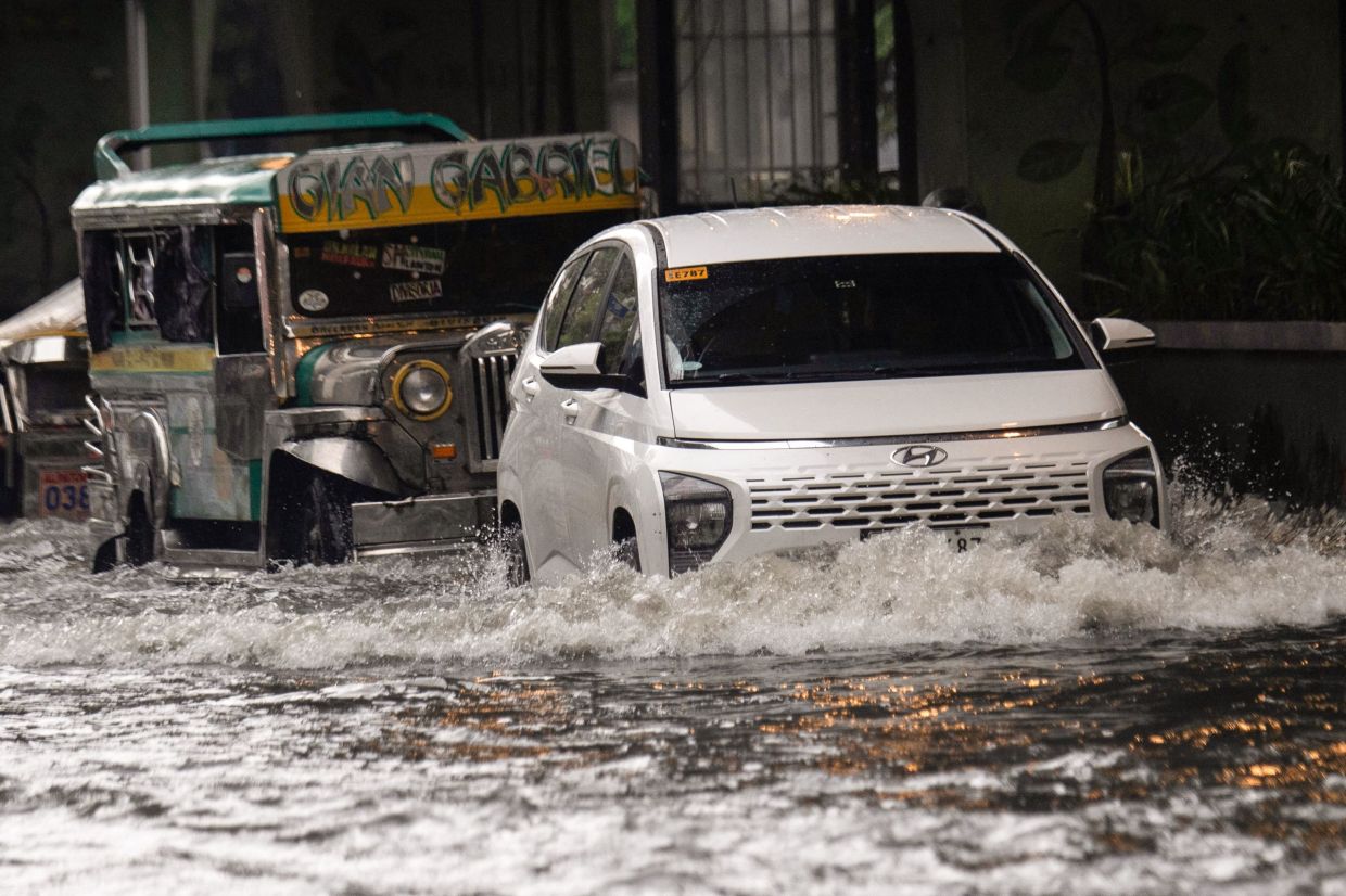 Motorists commute along a flooded street after heavy rain in Manila on Monday, August 10, 2026. -- Photo by Ted ALJIBE / AFP