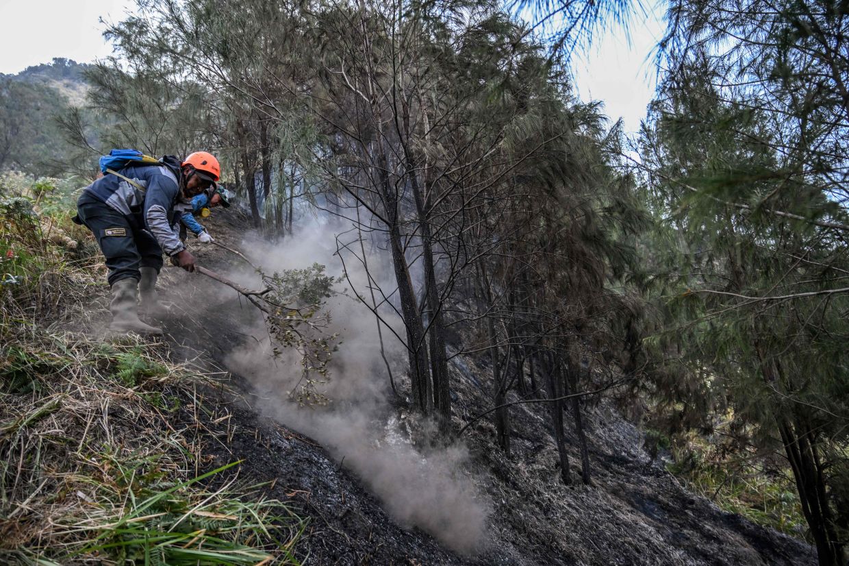 TOPSHOT - Volunteers battle a wildfire in the Bromo Tengger Semeru National Park near Mount Bromo in Pasuruan, East Java province, on Monday, August 10, 2026. -- Photo by JUNI KRISWANTO / AFP