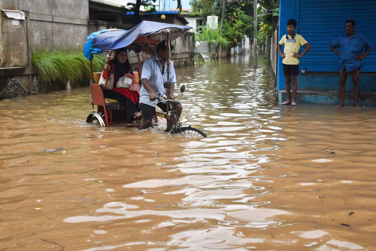 A resident commutes in a cycle rickshaw through a flooded street following heavy rainfall in Guwahati. Floods in India's northeast have killed nearly 100 people, according to an official toll update on August 7, with villages buried in mud after one of Assam state's worst deluges in years. -- Photo by Biju BORO / AFP