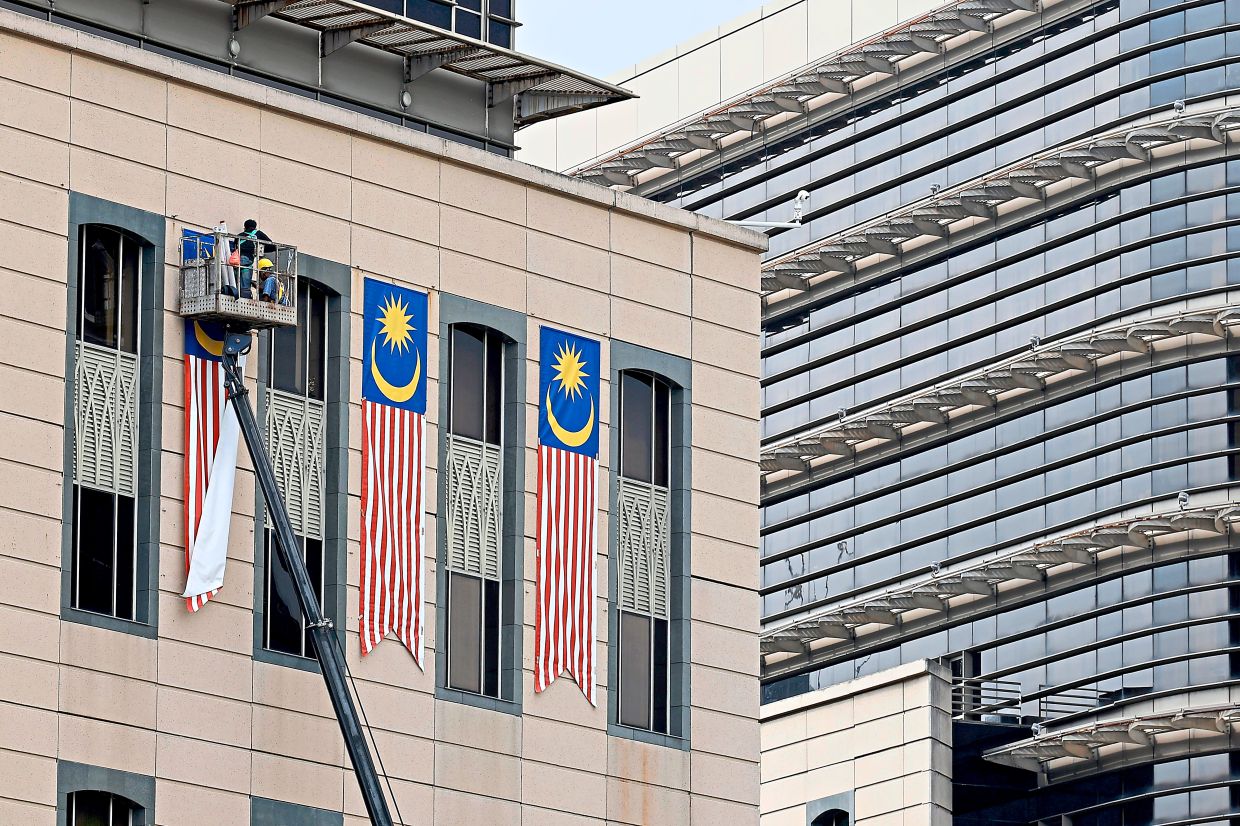 1. A worker putting up the Jalur Gemilang on federal buildings in Putrajaya ahead of Merdeka Day, as the nation prepares to mark another year of independence. — Bernama