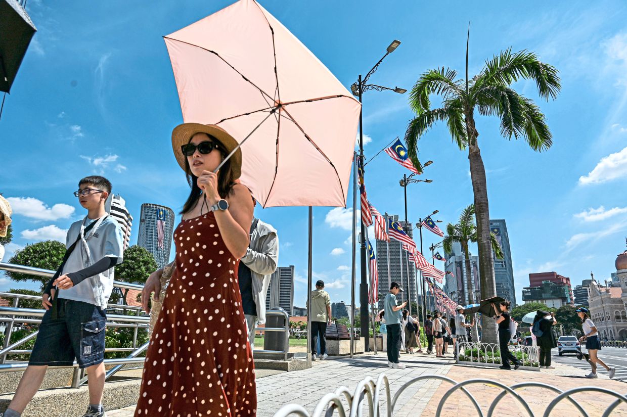 4. Foreign tourists strolling through Dataran Merdeka in Kuala Lumpur, with buildings adorned with the Jalur Gemilang providing a festive backdrop ahead of the National Day celebrations. — Bernama