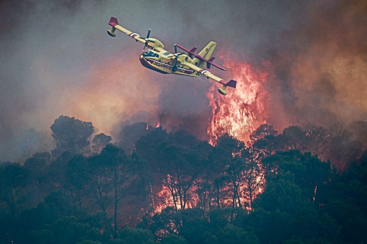 2. A French Civil Security Canadair CL-415 aircraft flying over flames consuming a forest near Cotignac, southeastern France. France has endured three heatwaves since May, with increasingly frequent extreme weather linked to climate change fuelling wildfires and causing thousands of excess deaths. — AFP