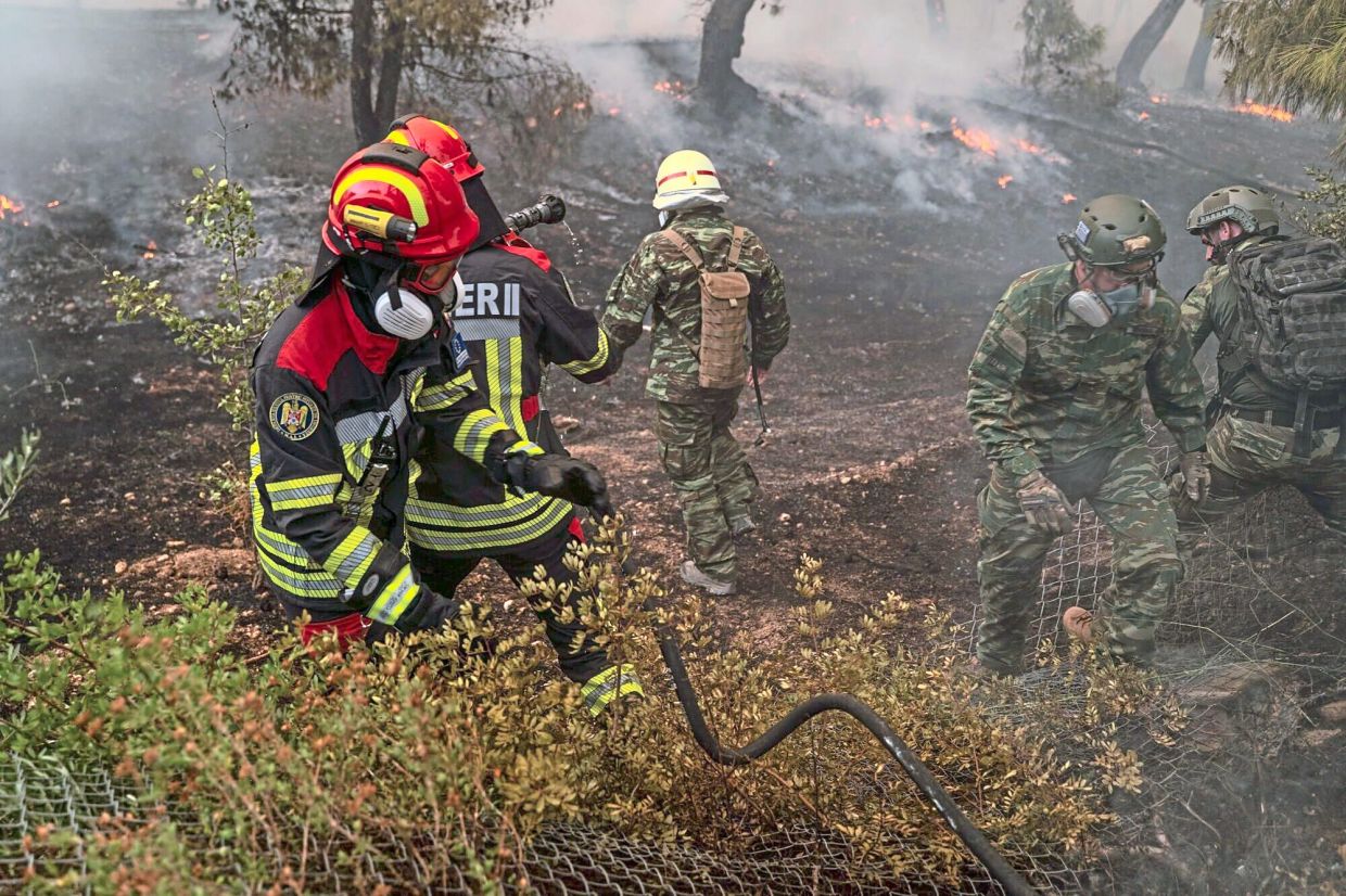 4. Romanian firefighters and volunteers working to contain a wildfire near a house in Loumpa, West attica, greece. greece has repeatedly called in foreign firefighters and rescue teams to help battle major wildfires during increasingly severe fire seasons. — Bloomberg