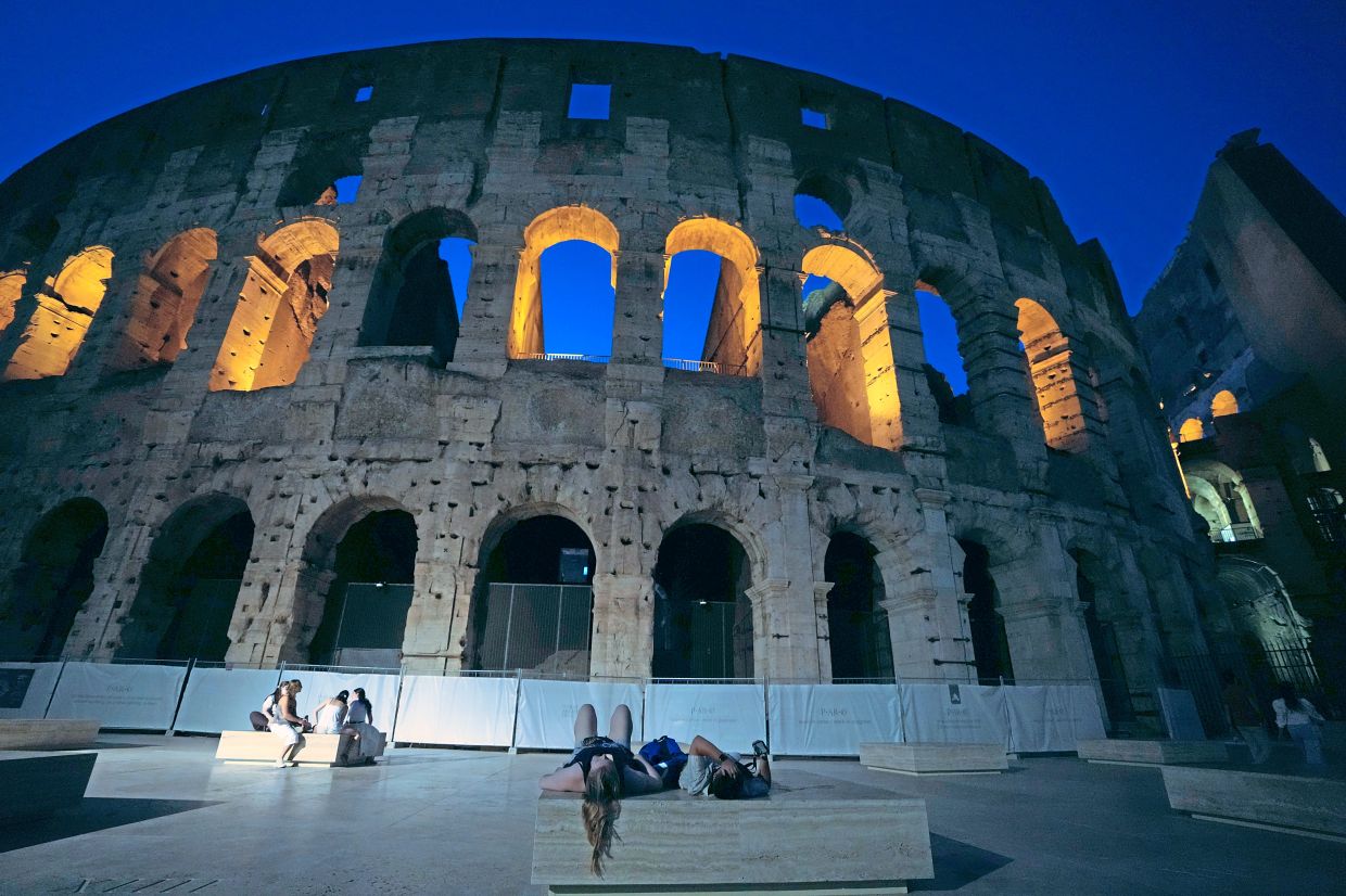 8. Tourists resting outside Rome’s Colosseum as the Italian archaeological site extends evening visits to help visitorsescape the daytime heat. — AP