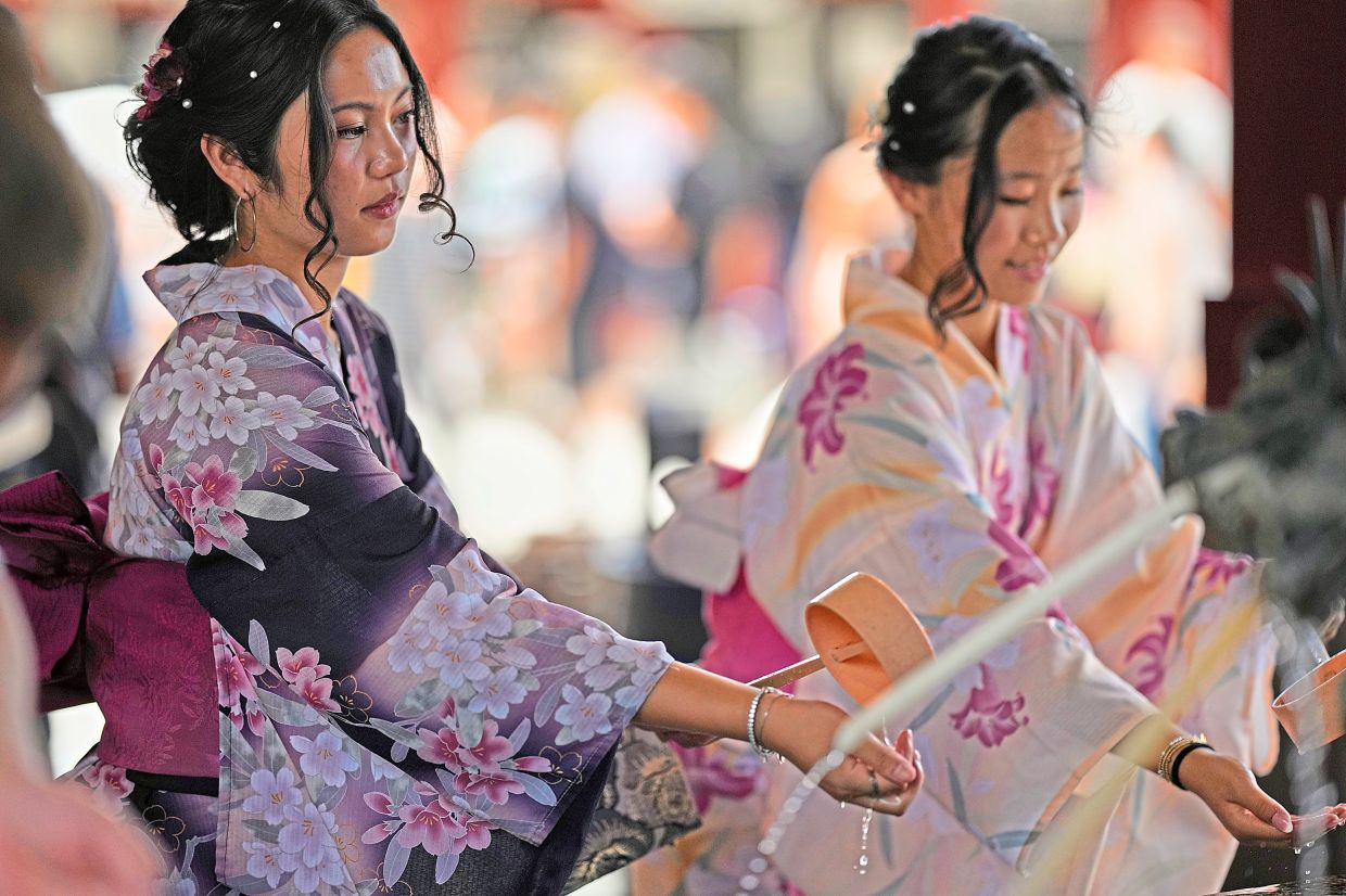4. Women washing their hands at a purification fountain at sensoji Buddhist temple on a hot, sunny day in Tokyo’s Asakusa district, Japan. — AP