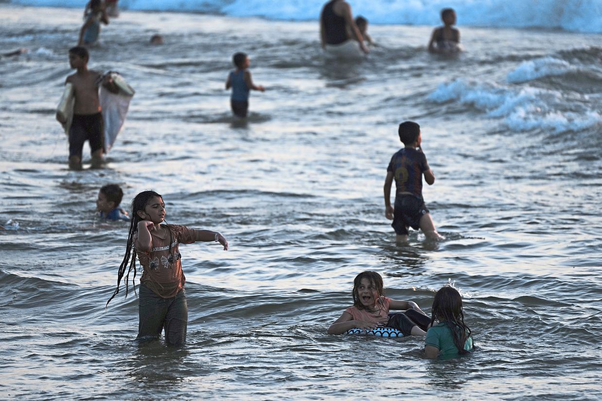 1. Palestinians cooling off in the Mediterranean Sea during a heatwave in Gaza City. — AP