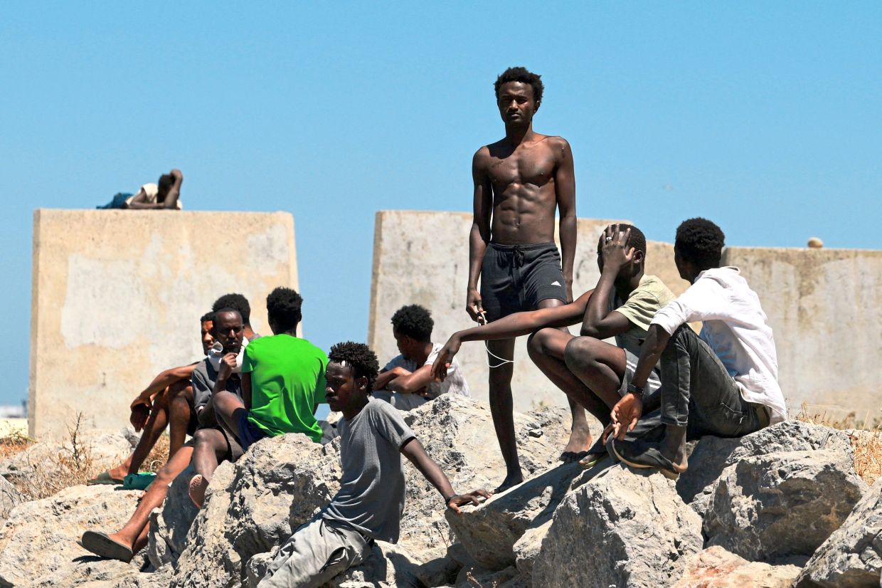 4. Migrants waiting along a breakwater on a beach in Ceuta, following a mass influx from Morocco. — Reuters