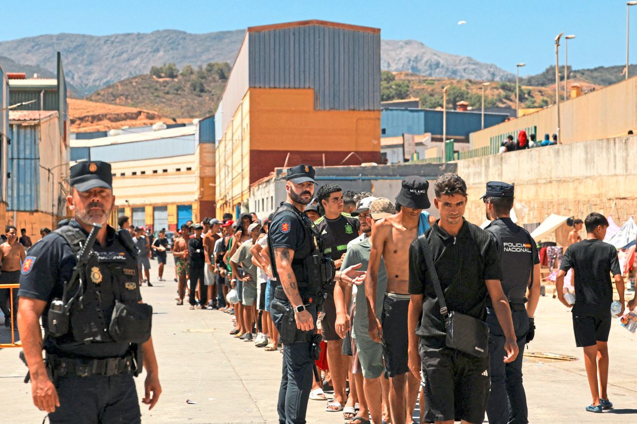 3. Migrants receiving for basic food supplies distributed by local NGO Media Luna Blanca at an industrial area where they have been sleeping. Those who remain in Ceuta face dire conditions, with limited access to food, water, shelter and sanitation. — Reuters
