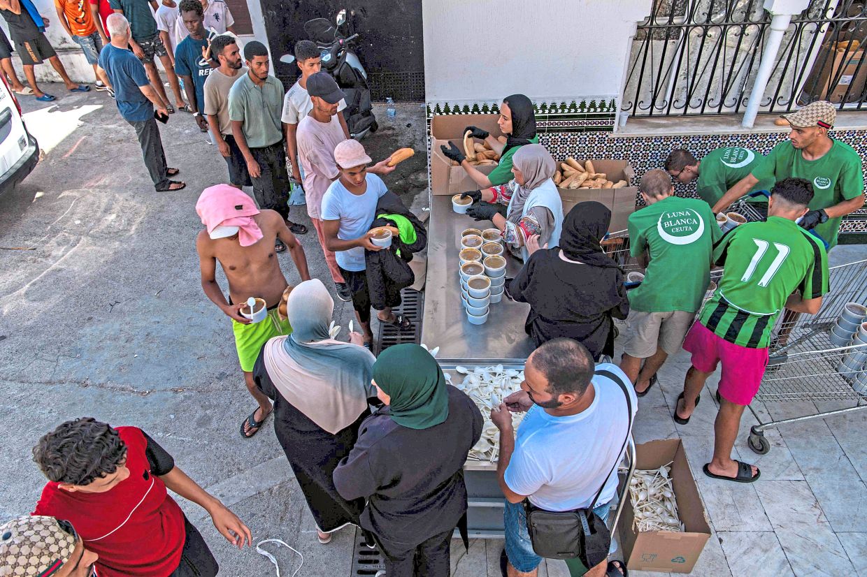 2. Migrants waiting for food distributed by NGO Luna Blanca in Ceuta, A spanish enclave on Morocco’s northern coast. — AFP