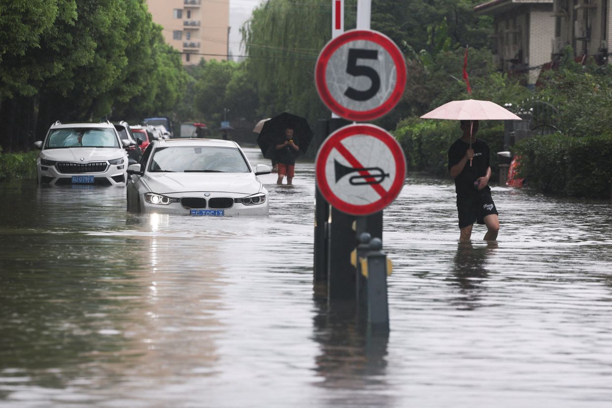 People wading through a flooded street after Typhoon Dolphin brought heavy rain to Shanghai on Aug 10, 2026. - Reuters