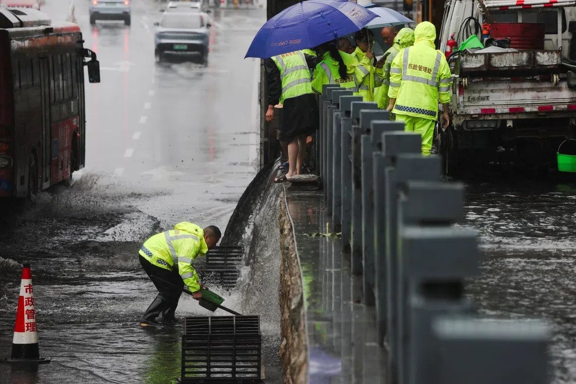 Workers from the city management department work to unclog a drain at a flooded underpass during heavy rain brought by Typhoon Dolphin after it weakened into a tropical storm in Xiangyang, Hubei province, China, August 11, 2026. - Photo: Reuters
