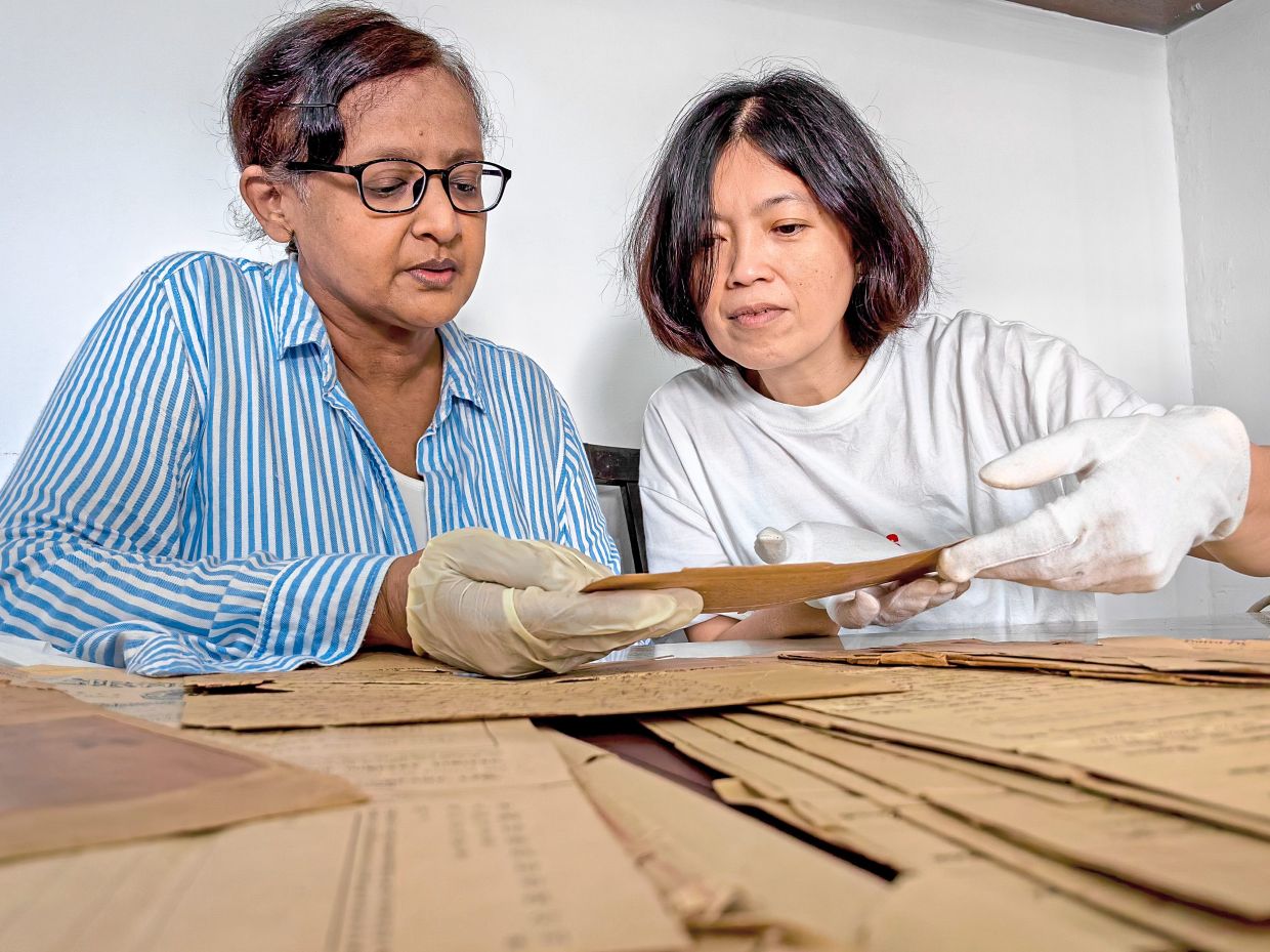 Lee (right) examining a century-old legal document kept by Geeta while offering advice on proper paper conservation techniques.